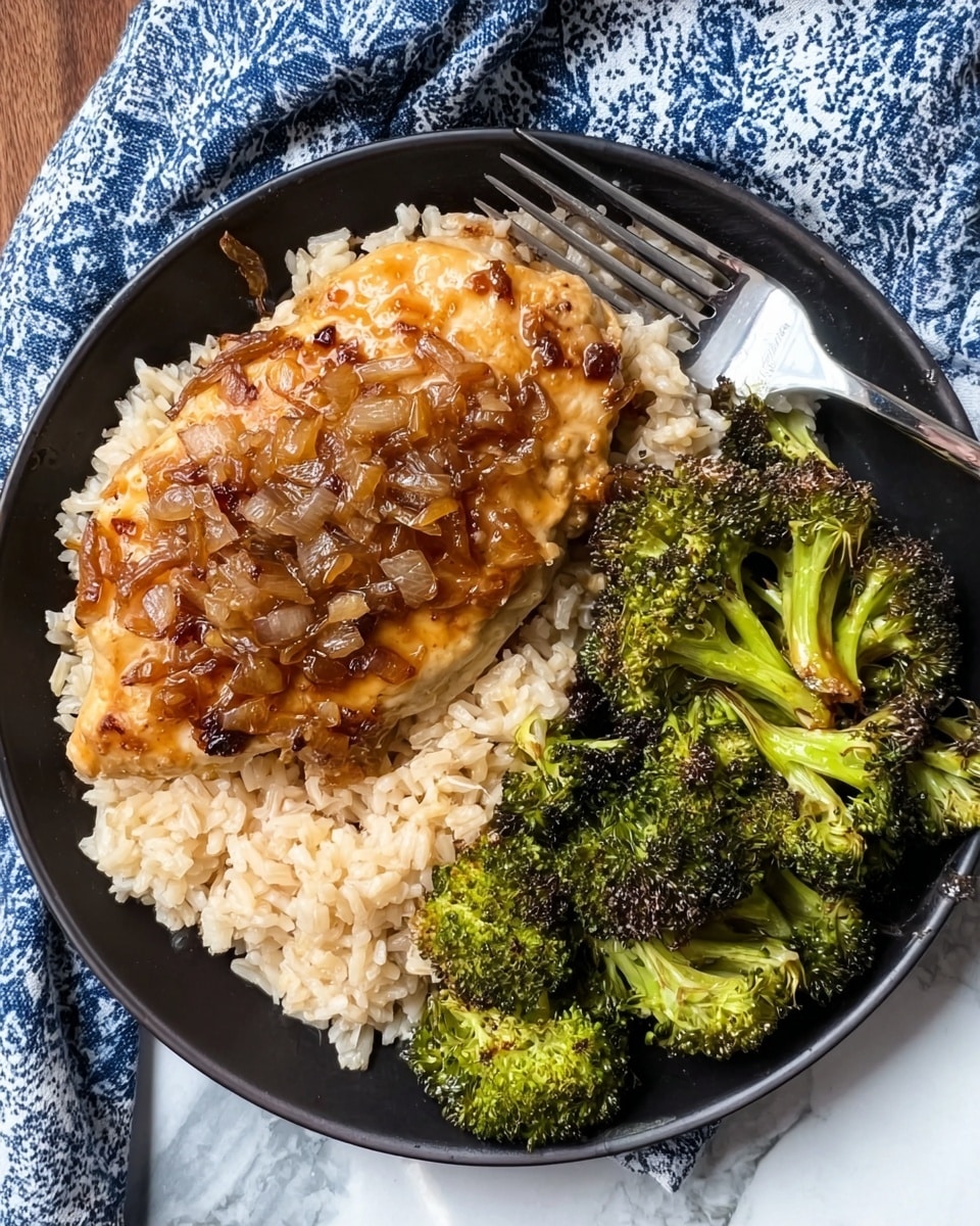 A black round plate is filled with three main layers: a base of creamy light beige rice with a soft texture, topped with a large piece of glazed golden-brown chicken breast covered with bits of caramelized onions, and a generous side of roasted broccoli florets with bright and dark green colors and slightly charred edges. A silver fork rests on the right side of the plate. The plate is placed on a white marbled surface with a blue and white patterned cloth nearby. Photo taken with an iphone --ar 4:5 --v 7