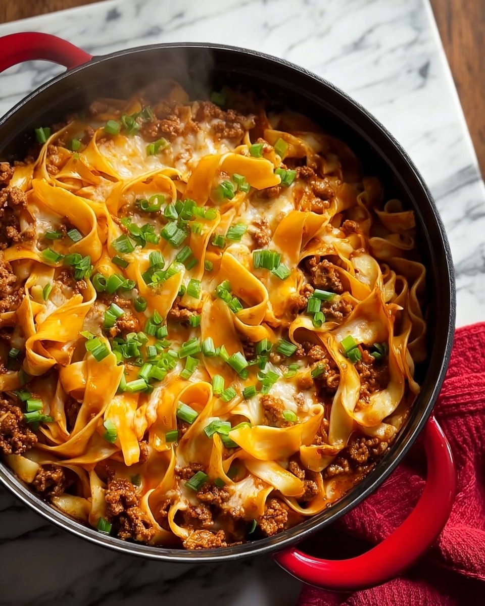 The image shows a black pot filled with cooked pasta and ground meat mixed together. On top of this base layer of orange pasta and brown meat, there are several folded slices of melted bright orange cheese positioned in the center. The dish is finished with chopped green onions scattered over the cheese, adding a fresh green color contrast. The pot is placed on a white marbled surface with a red cloth partially visible on the right side. Steam rises gently from the hot food. Photo taken with an iphone --ar 4:5 --v 7