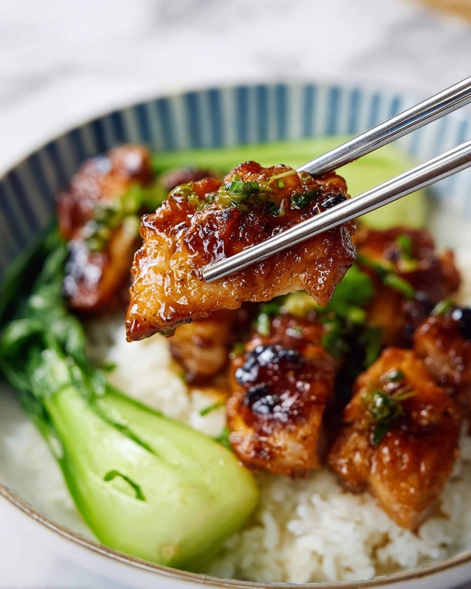 A close-up of a piece of grilled chicken with a shiny, caramelized surface and small green herb bits held by metal chopsticks, above a bowl filled with several similar golden-brown grilled chicken pieces on a bed of white rice, next to neatly arranged bright green sliced bok choy, all served in a white bowl with a blue striped pattern on the inside edge, placed on a white marbled surface. photo taken with an iphone --ar 4:5 --v 7