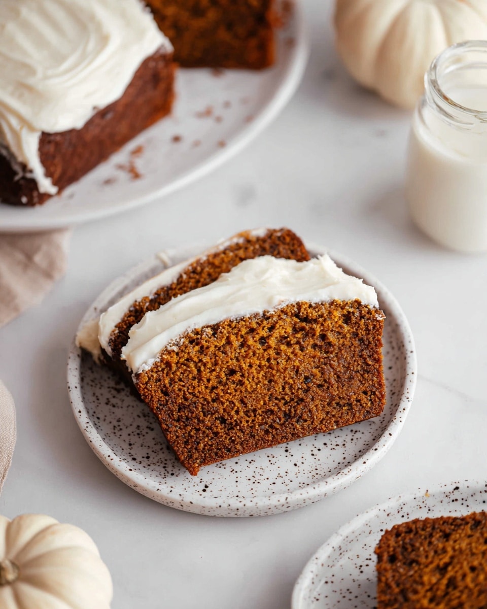 A close-up of a single thick slice of brown pumpkin bread with visible small holes and a slightly crumbly texture, topped with a smooth, creamy white layer of frosting that covers the top part of the bread and slightly spills over the sides, all placed on a white speckled plate. In the background, there is a white pumpkin, a small white bottle filled with milk, and parts of other plates holding similar slices of pumpkin bread with frosting, all set on a white marbled surface. photo taken with an iphone --ar 4:5 --v 7