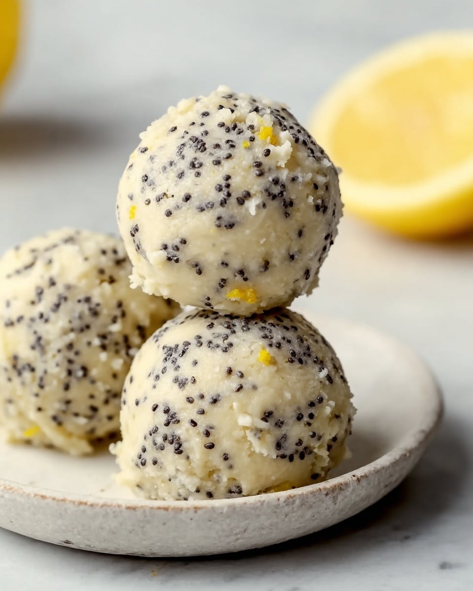 The image shows a close-up of four round lemon poppy seed balls stacked in a pyramid shape on a white speckled plate. Each ball is light yellow with small black poppy seeds spread evenly across the surface, giving a textured look. Around the balls, there are bright yellow lemon wedges with white rind, placed on the plate for decoration. The background is soft and out of focus with a white marbled texture underneath the plate, highlighting the fresh and bright colors. photo taken with an iphone --ar 4:5 --v 7